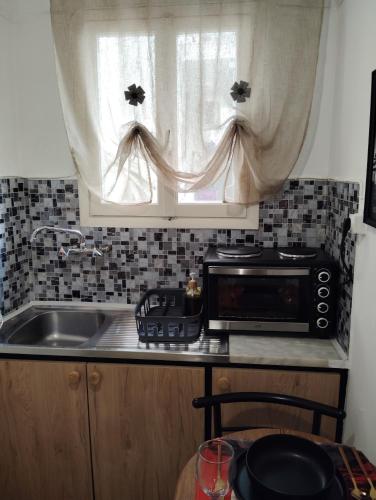 a kitchen with a microwave and a sink and a window at Tiny Japan in Volos