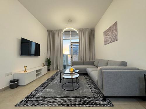 a living room with a couch and a table at Cozy 1BR Pool-Gym, close to metro BrandNew! in Dubai