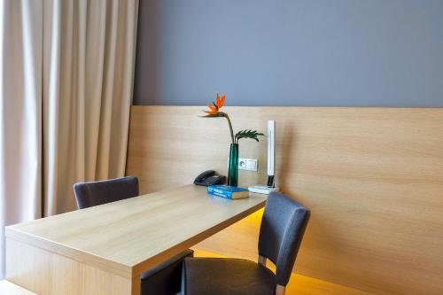 a table with chairs and a vase with a flower on it at Hotel MDM City Centre in Warsaw