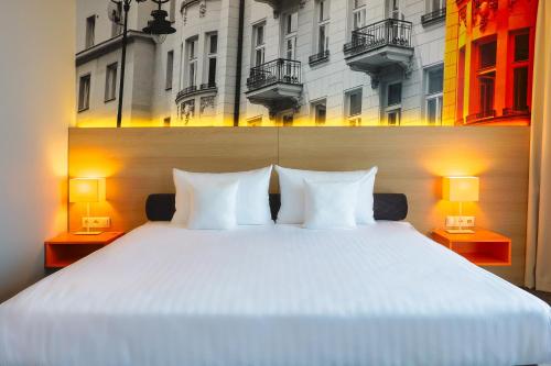 a bedroom with a large white bed with two lamps at Hotel MDM City Centre in Warsaw