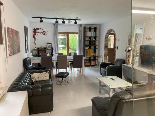 a living room with leather furniture and a dining room at Perk25A in Steenokkerzeel