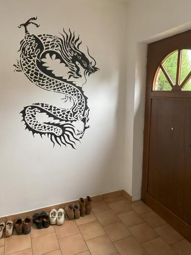 a black dragon stencil on a wall next to shoes at Perk25A in Steenokkerzeel