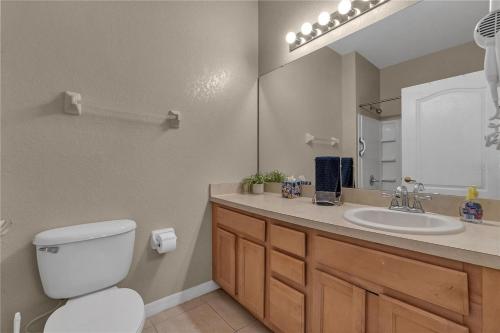 a bathroom with a toilet and a sink and a mirror at Enjoy my cozy house next to Disney in Kissimmee