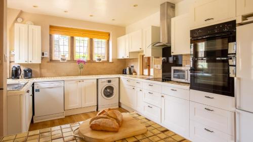 a kitchen with white cabinets and a washer and dryer at Arlington House in Lower Slaughter