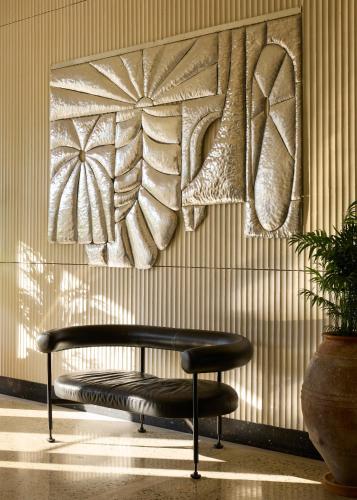 a bench sitting in front of a wall with a painting at Ace Hotel & Swim Club Athens in Athens