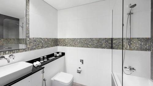 a bathroom with a toilet and a sink and a shower at The First Collection Dubai Marina in Dubai