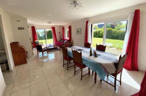 une salle à manger avec une table et quelques rideaux rouges dans l'établissement CARANTEC MAISON FAMILIALE AVEC JARDIN 9 personnes, à Carantec