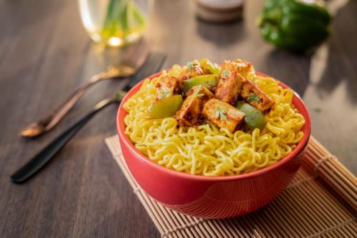 a red bowl of noodles with tofu and green peppers at Sherpa Retreat Resort in Padamchen