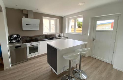 - une cuisine avec un comptoir et des tabourets dans l'établissement Saint-Pol maison familiale avec jardin équipée à neuf 12 personnes, à Saint-Pol-de-Léon