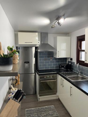 a kitchen with a sink and a stove top oven at Oysterman's Cottage in The Mumbles