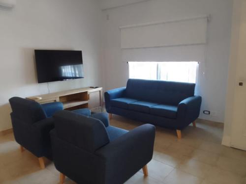 a living room with blue chairs and a tv at Tigre Centro Cochera Gratis in Tigre