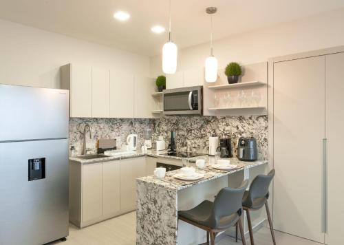 a kitchen with white cabinets and a counter with chairs at Park View Loft in Panama City