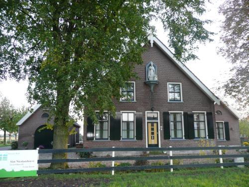 a brick house with a tree in front of it at Sint Nicolaashoeve in Nieuwveen