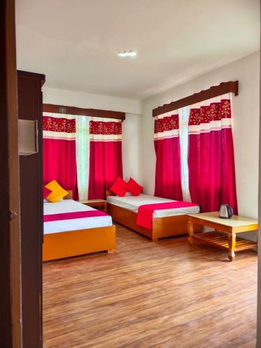 two beds in a room with red curtains at Sherpa Retreat Resort in Padamchen