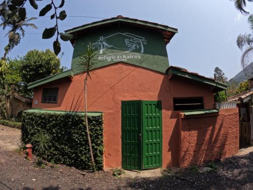 a building with a green door in front of it at Refúgio do Kairós in Ubatuba
