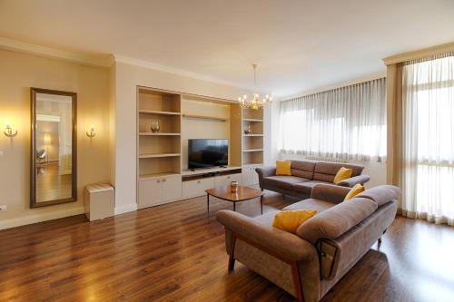 a living room with a couch and a tv at The Rooms Serviced Apartments Tirana in Tirana