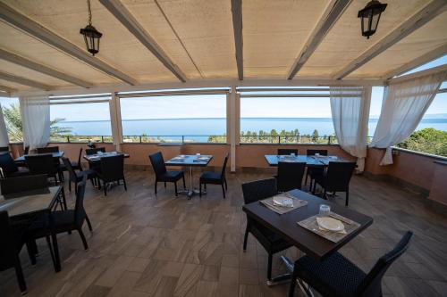 Un restaurante con mesas y sillas y vista al mar. en UNICO Cannamele Escape Tropea by Life Resorts, en Parghelia