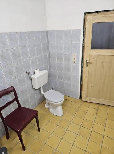 a bathroom with a toilet and a chair and a door at Rustikales Landhaus in Colmberg