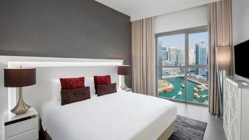 a bedroom with a white bed and a large window at The First Collection Dubai Marina in Dubai