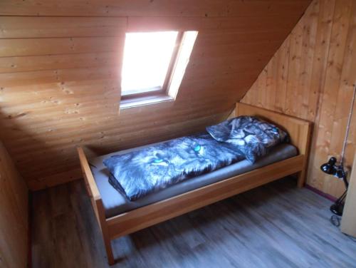 a bed in a wooden room with a window at Rustikales Landhaus in Colmberg