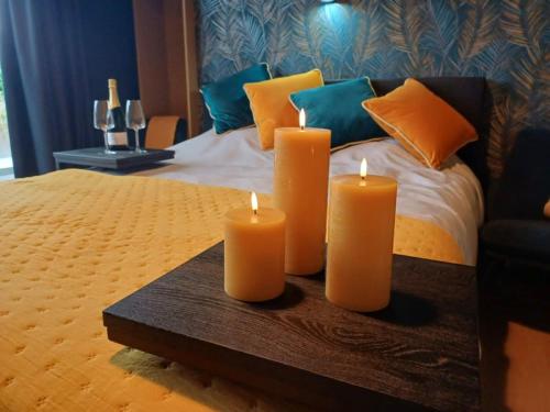 three candles on a table in front of a bed at ' t Geel Huizeken - B&B - koffiehuis in Denderleeuw