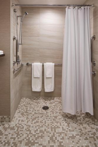 a bathroom with a shower with towels and a shower curtain at The Del Monte Lodge Renaissance Rochester Hotel & Spa in Rochester