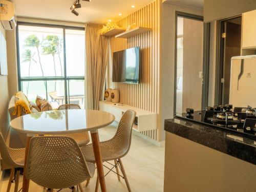 a kitchen and living room with a table and a table and chairs at Flat pé na areia na praia de Porto de Galinhas próximo as piscinas naturais. in Porto De Galinhas