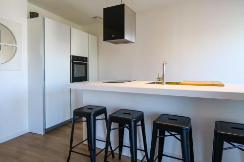 une cuisine avec quatre tabourets noirs à un comptoir dans l'établissement Joli appartement rénové sur le port de pêche avec une superbe vue sur le port des Sables - 4 personnes, à Les Sables-dʼOlonne