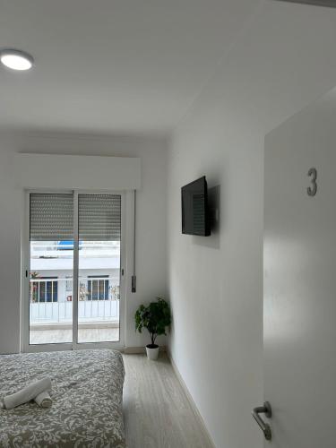 a white bedroom with a bed and a window at GrowIN Stay Mercado in Faro