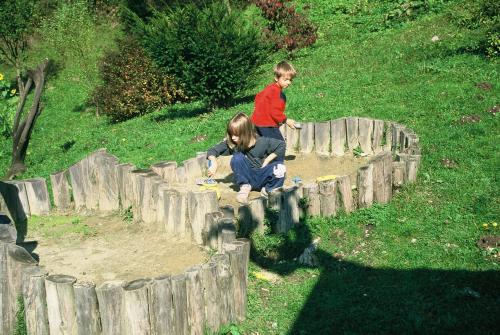 two young children playing in a wooden fence at Guest House Kraljev Hrib in Kamniška Bistrica