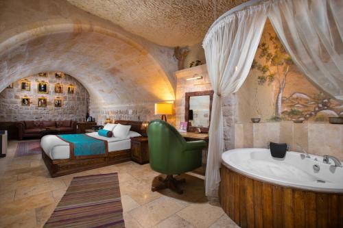 a bedroom with a bed and a tub in a room at Cappa Via Cave Hotel in Urgup