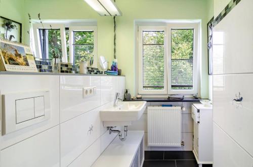 a white bathroom with a sink and windows at Ferienwohnung Refugium Nest in Sigmaringen