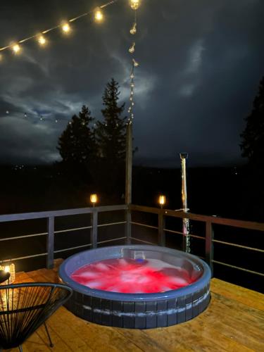 a hot tub on a deck at night at La KOLTAU A-Frame in Mărişel
