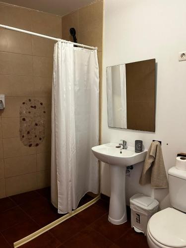 a bathroom with a white shower curtain and a sink at Avis Guesthouse in Évora