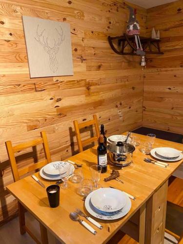 une table en bois avec des assiettes et des verres à vin dessus dans l'établissement Appartement 4-6 pers - La Bourboule, à La Bourboule