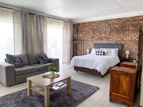 a bedroom with a bed and a brick wall at Cozy Cottage in Langebaan