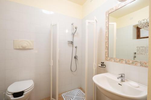 a white bathroom with a shower and a sink at Borgo Badia by VacaVilla in Badia