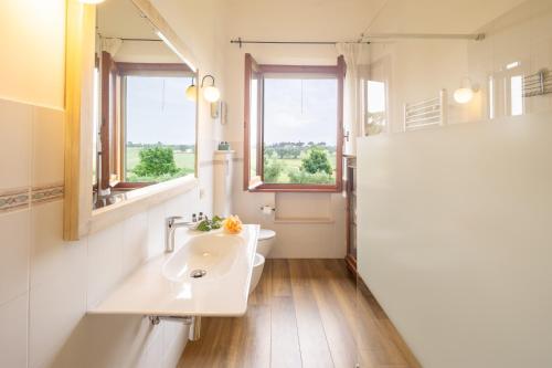 a bathroom with a sink and two windows at Borgo Badia by VacaVilla in Badia