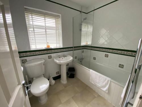 a white bathroom with a toilet and a sink at The Bungalow at Parkside, 4 ensuite bedrooms in Goole