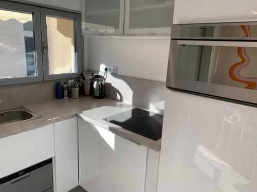 une cuisine blanche avec un évier et un micro-ondes dans l'établissement Charmant studio Croisette, à Cannes