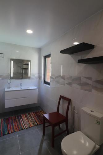 a bathroom with a toilet and a sink and a chair at Quinta do Chão do Vale in Sever do Vouga
