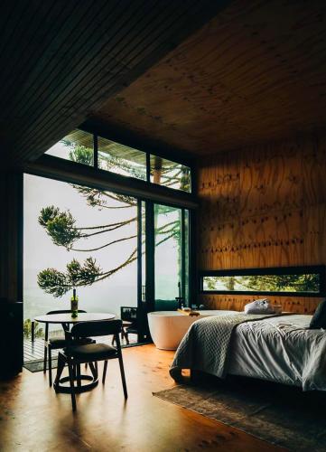 a bedroom with a bed and a tub and a table at Cabanas Terrunyo - Cabana Bela in Urubici