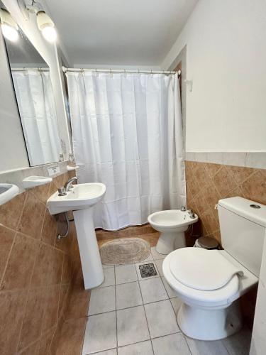 a white bathroom with a toilet and a sink at Amplia casa en la 5ta sección ciudad con patio y parrilla in Mendoza