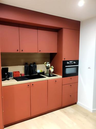 une cuisine avec des armoires rouges et un appareil noir dans l'établissement gite paisible à la ferme, à Sainte-Honorine-de-Ducy