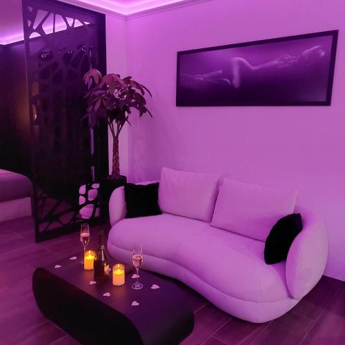 a purple living room with a couch and a table at LA NUIT DES SECRETS Love Room 4 étoiles avec Jacuzzi et Sauna in Roquebrune-sur-Argens