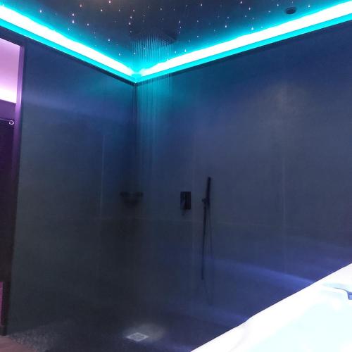 a dark room with a shower with blue lights at LA NUIT DES SECRETS Love Room 4 étoiles avec Jacuzzi et Sauna in Roquebrune-sur-Argens