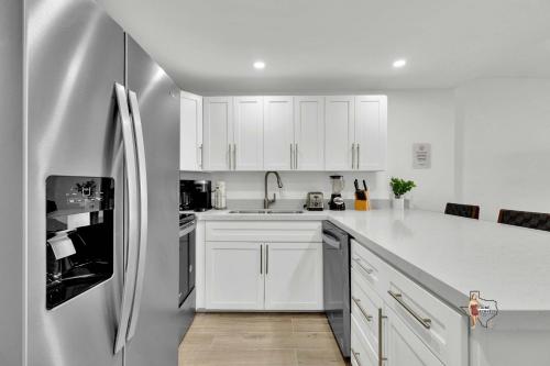 a kitchen with white cabinets and a stainless steel refrigerator at Bahia Mar Solare Beachfront Resort Condos with Two Pools in South Padre Island