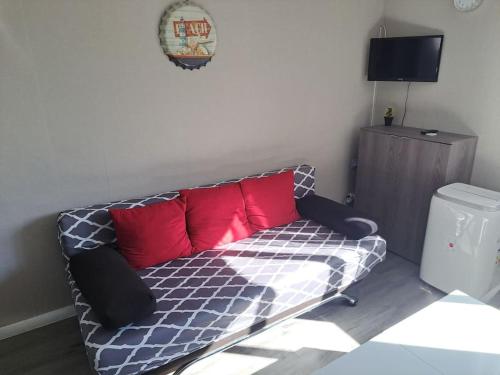 - un canapé avec des oreillers rouges dans l'établissement Asphodèle, Joli studio avec parking, 2 pas des plages et du Port, au Cap d'Agde