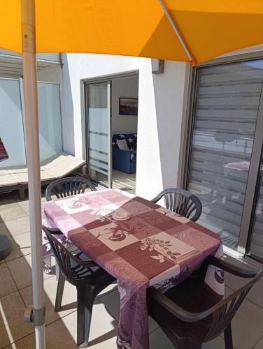 une table et des chaises avec un parasol sur un balcon dans l'établissement En bord de mer, à Berck-sur-Mer