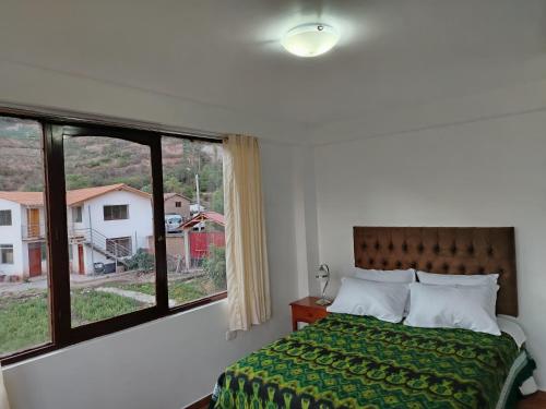 a bedroom with a bed and a large window at Casa de Campo Apu San Isidro in Urubamba